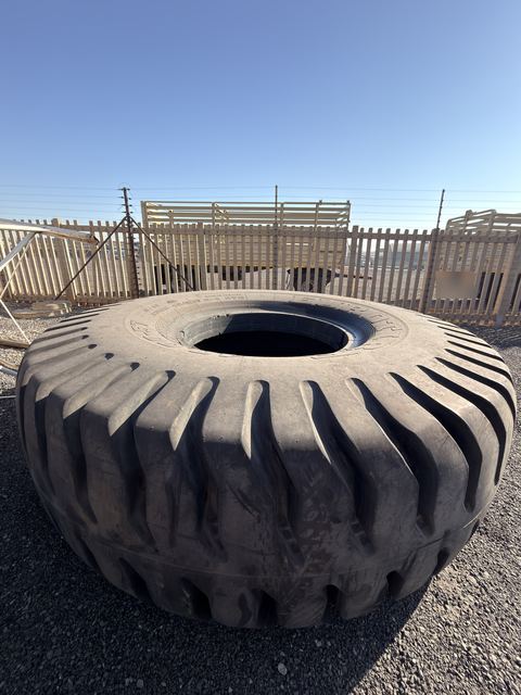 Single earthmover tyre lying flat on the yard, tread and sidewall in view