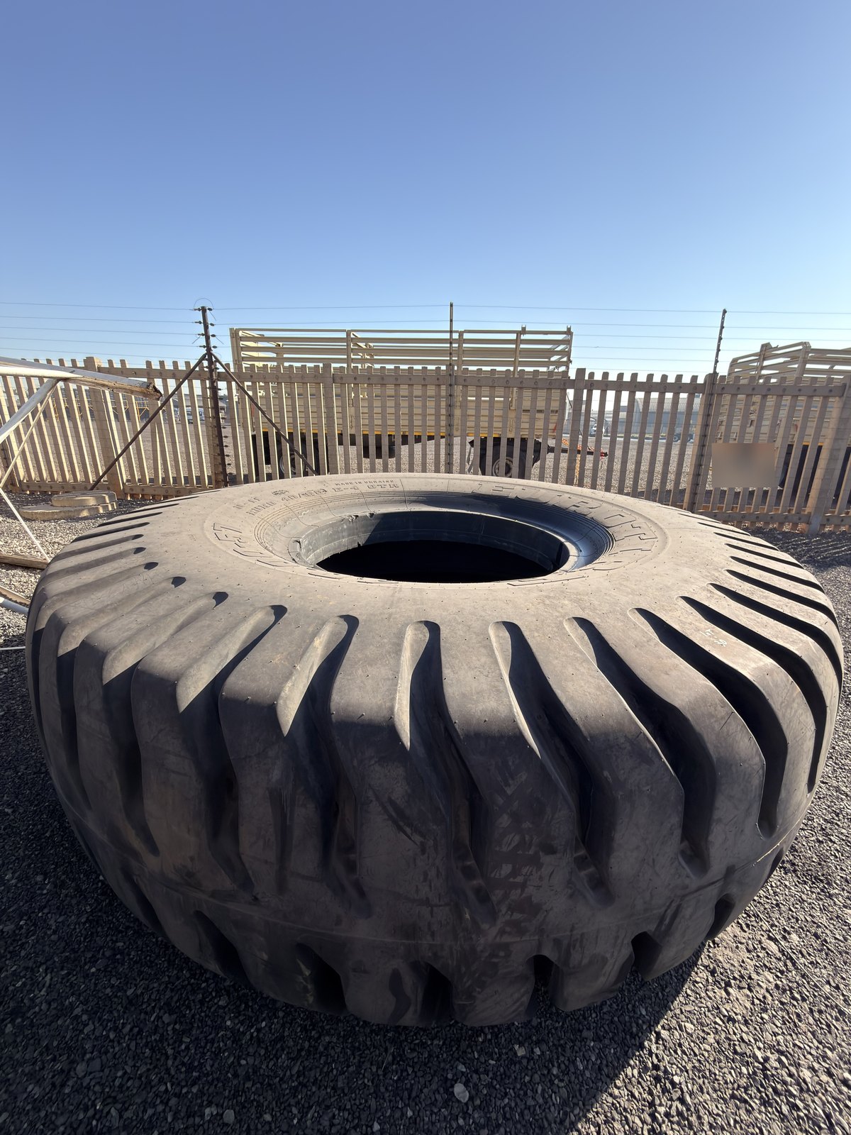 Single earthmover tyre lying flat on the yard, tread and sidewall in view
