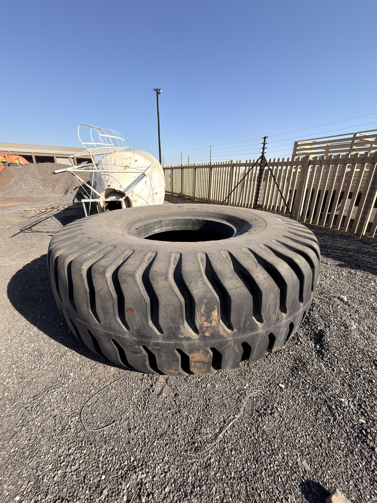 Single earthmover tyre lying on the gravel, angled view of the tread