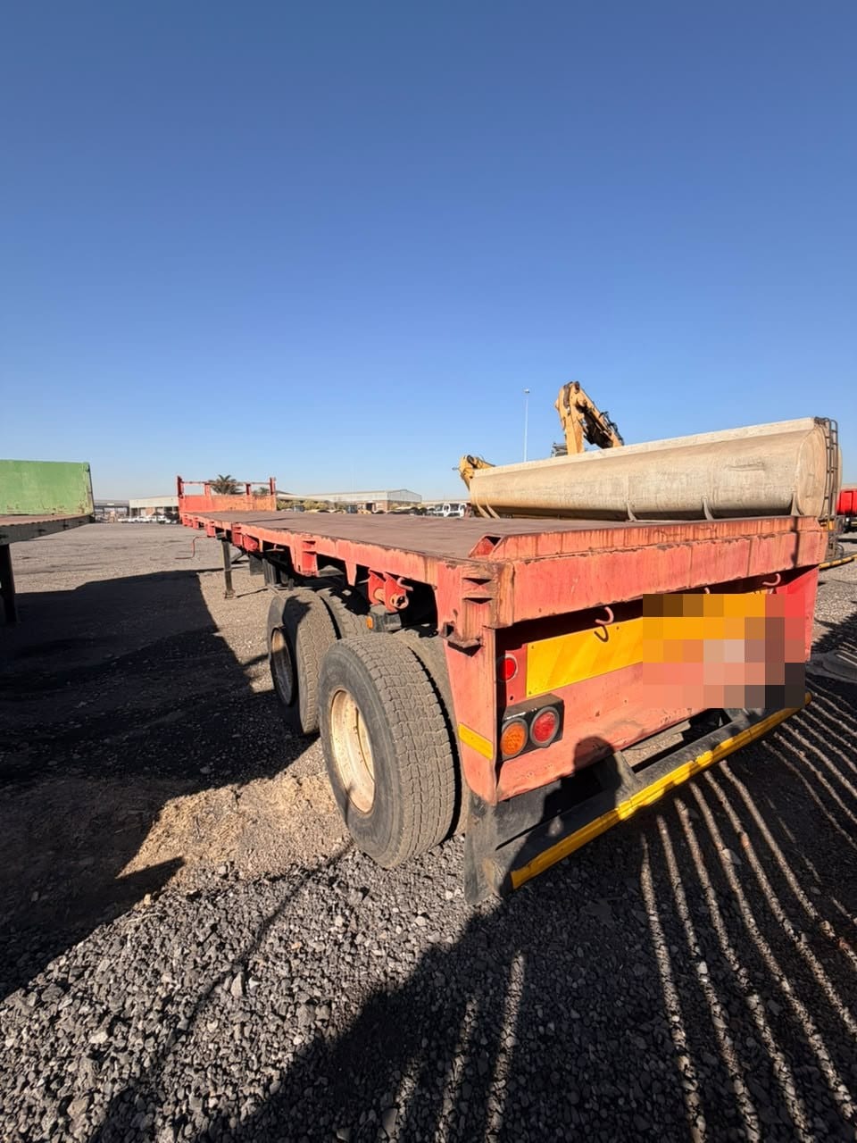 Used 12m flat deck trailer, rear three-quarter view showing the low dropsides and tandem axles