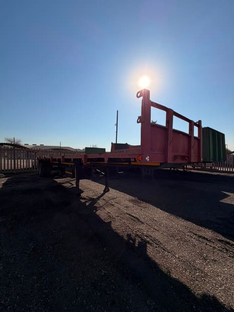Used 12m flat deck trailer, full length seen from the rear, into low sun