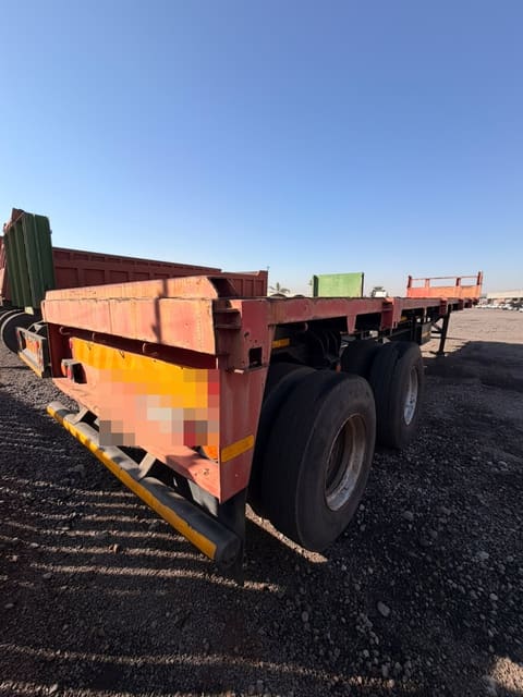Used 12m flat deck trailer, close rear three-quarter view of the tandem axles and rear lights