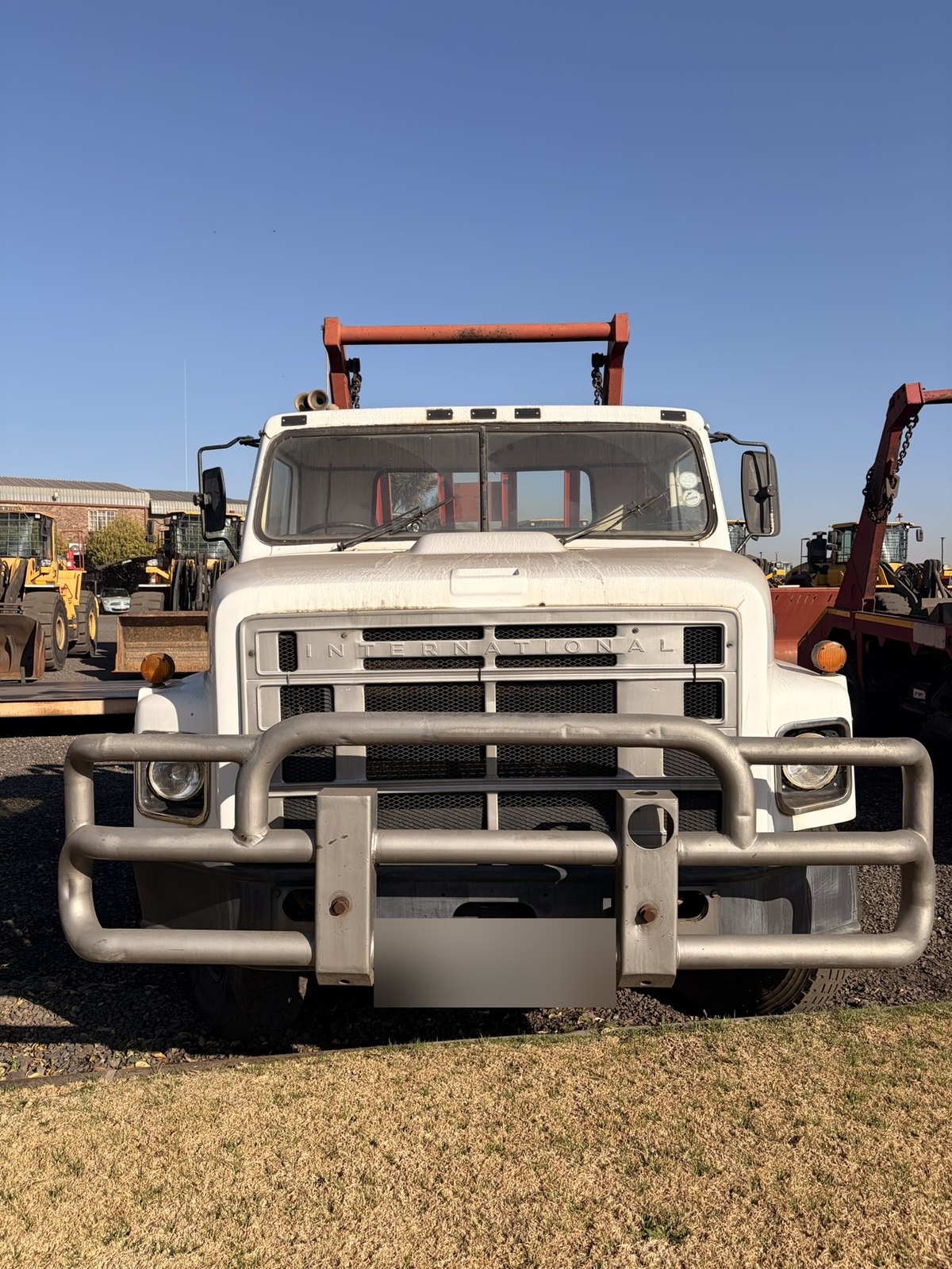 Used International skip loader truck, head-on view of the grille and cab