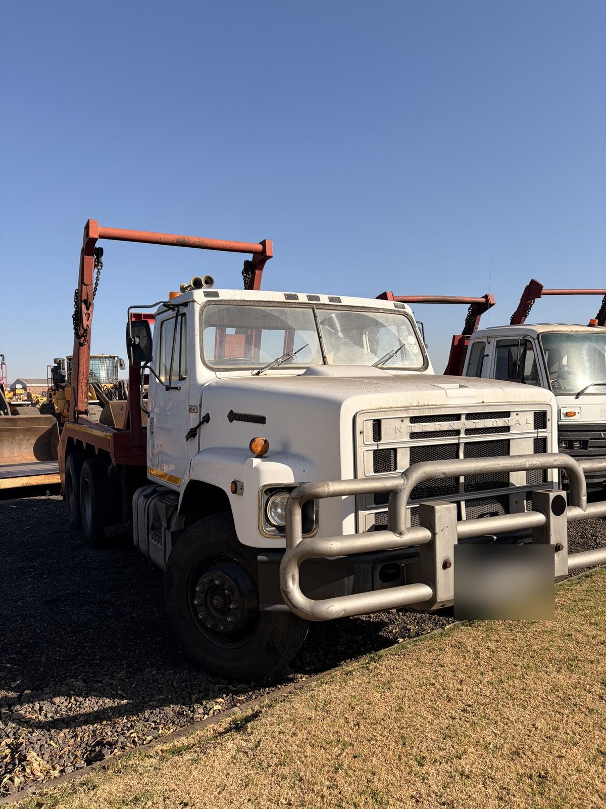 Used International skip loader truck, front three-quarter view of the cab and skip-loading gear