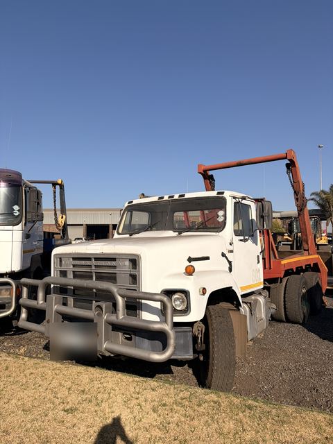 Used International skip loader truck, front three-quarter view standing in the yard