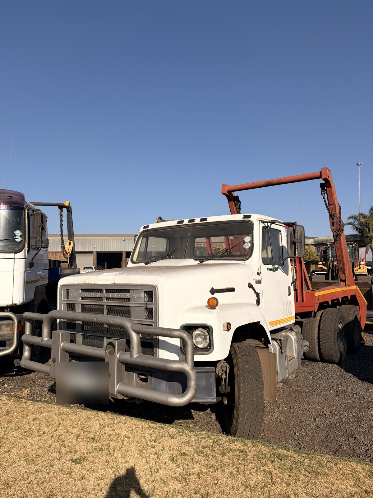 Used International skip loader truck, front three-quarter view standing in the yard