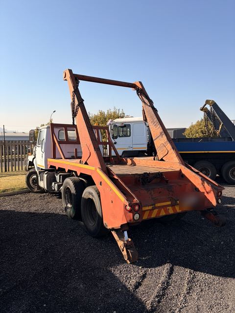 Used International skip loader truck, rear three-quarter view of the skip-loading gear