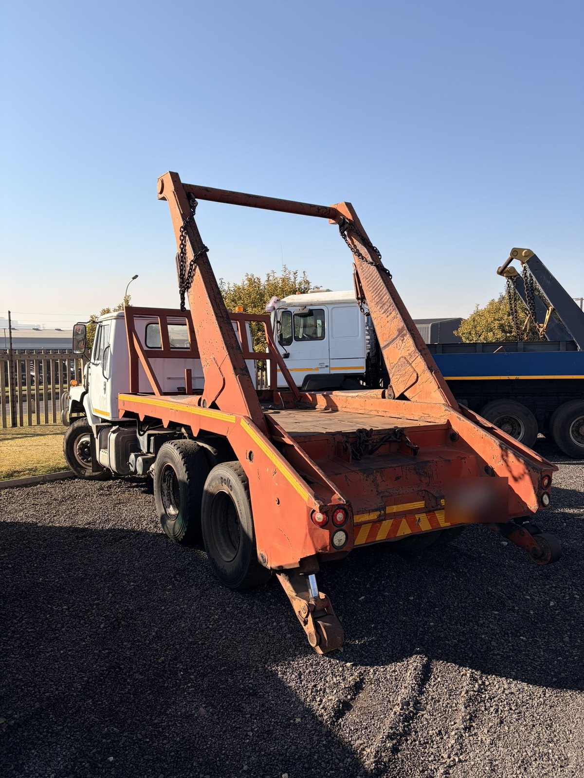 Used International skip loader truck, rear three-quarter view of the skip-loading gear