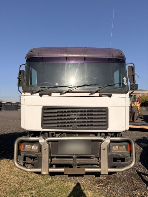 Used MAN skip loader truck, head-on view of the cab, grille and bull bar