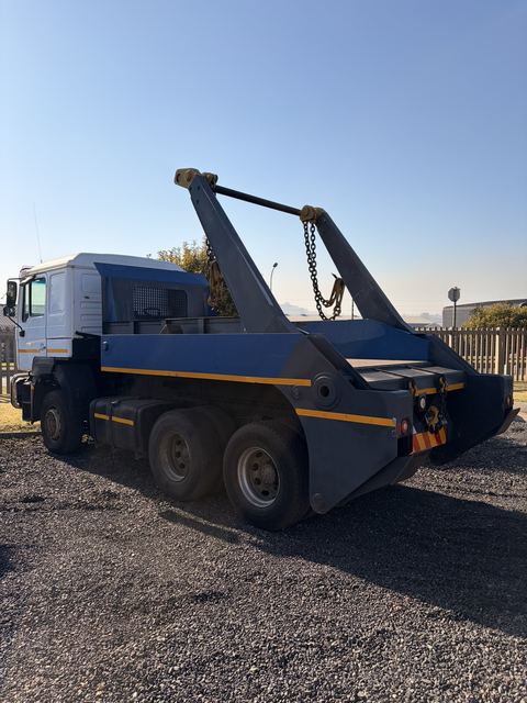 Used MAN skip loader truck, rear three-quarter view with the skip arms raised