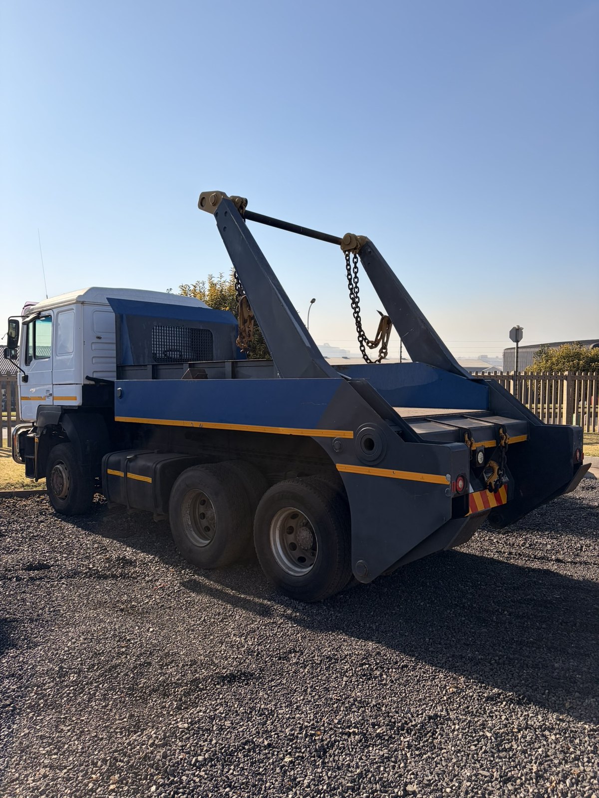Used MAN skip loader truck, rear three-quarter view with the skip arms raised