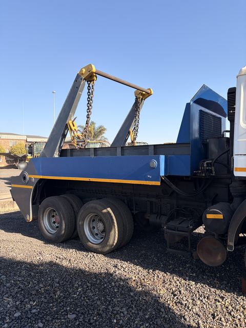 Used MAN skip loader truck, side view of the blue skip body and rear bogie