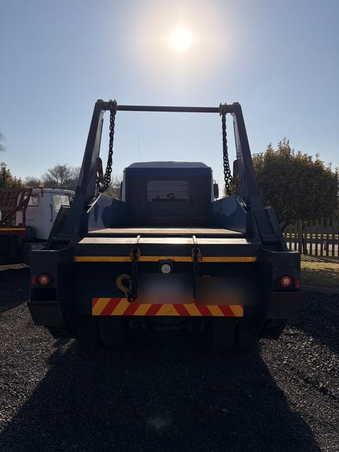 Used MAN skip loader truck, rear view of the deck, skip arms and chains