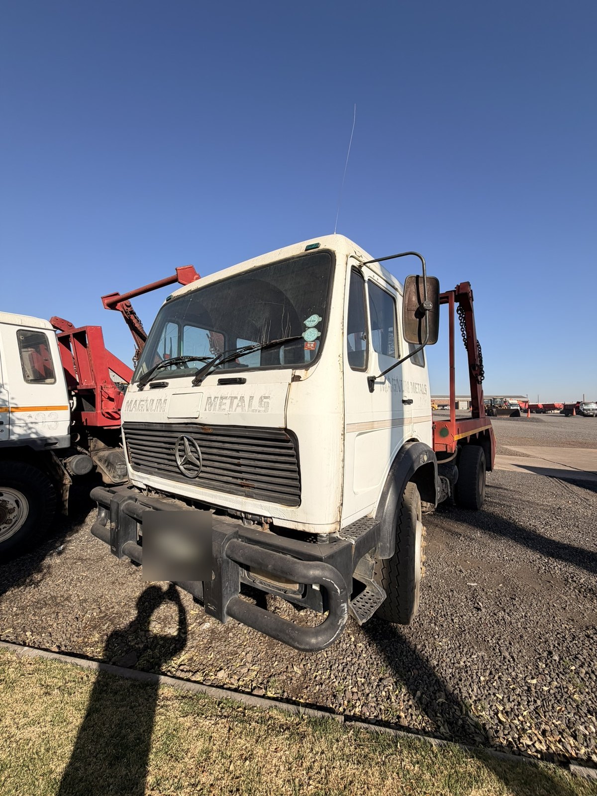 Used Mercedes skip loader truck, front three-quarter view with the skip-loading gear behind the cab