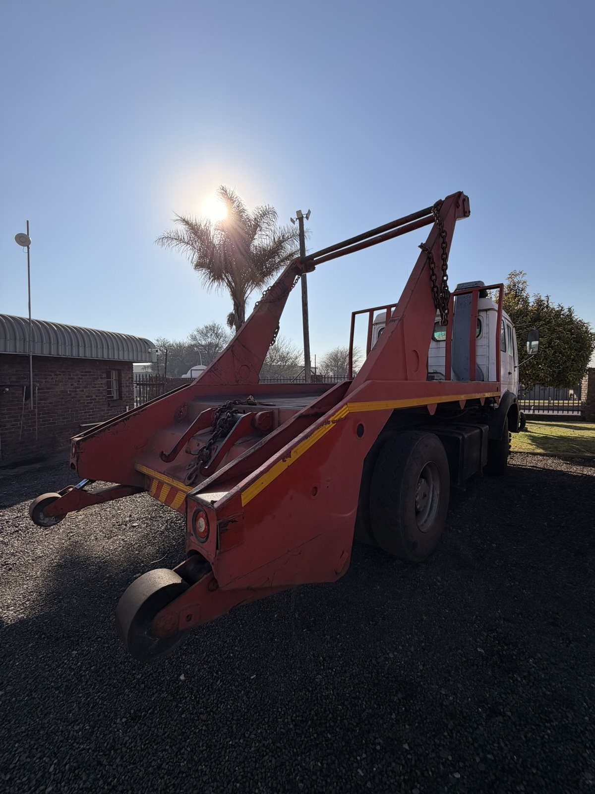 Used Mercedes skip loader truck, rear three-quarter view with the skip arms raised