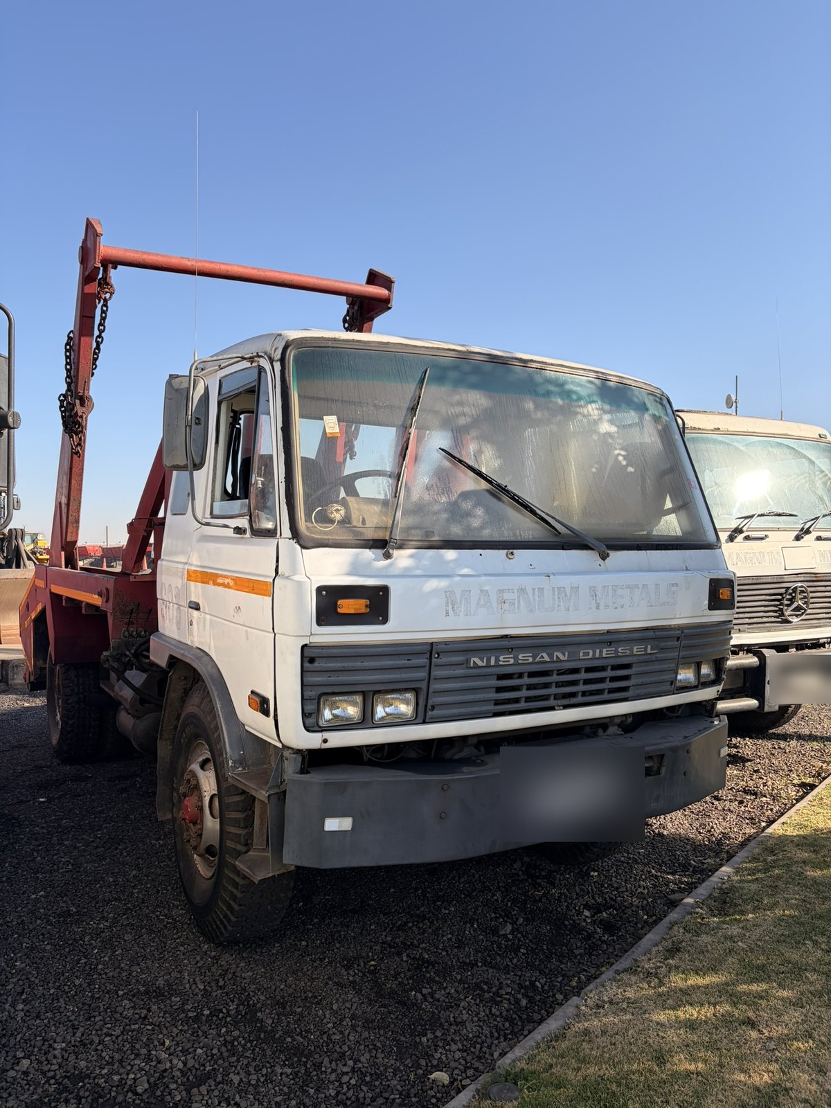 Used Nissan Diesel skip loader truck, front three-quarter view of the cab and skip-loading gear