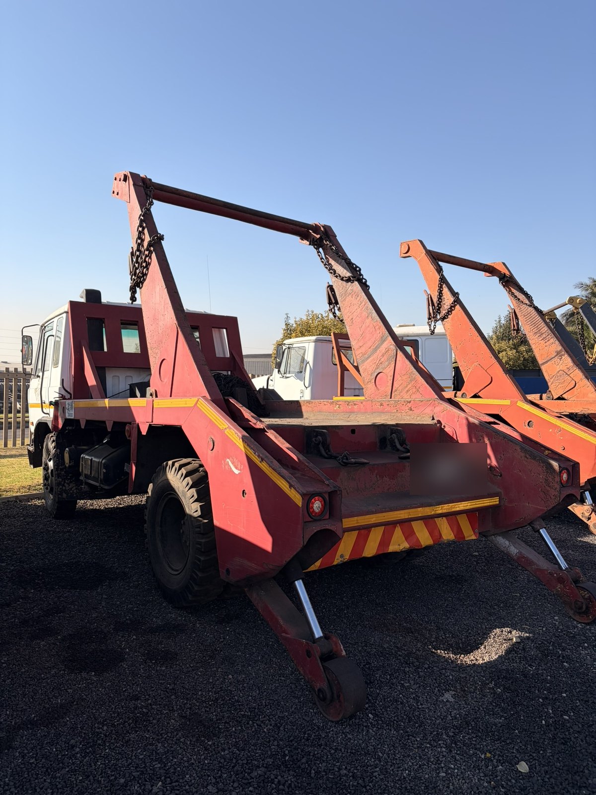 Used Nissan Diesel skip loader truck, rear three-quarter view of the skip arms and stabiliser legs