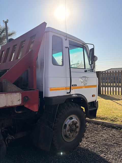 Used Nissan Diesel skip loader truck, side view of the cab and skip frame in the yard