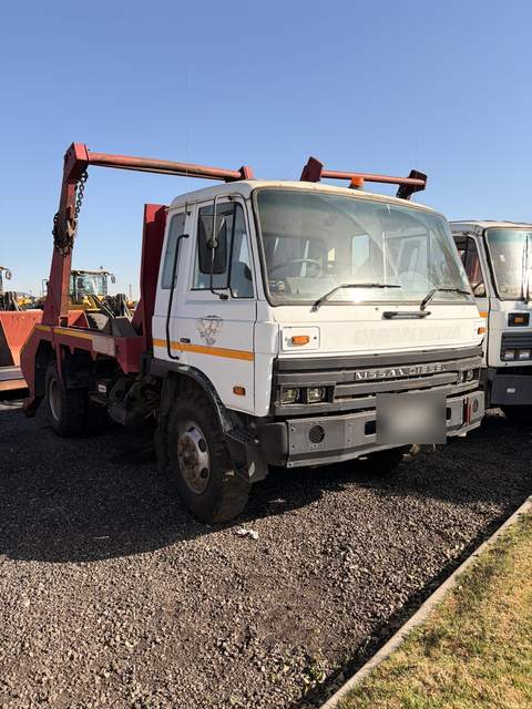 Second used Nissan Diesel skip loader truck, front three-quarter view in the yard