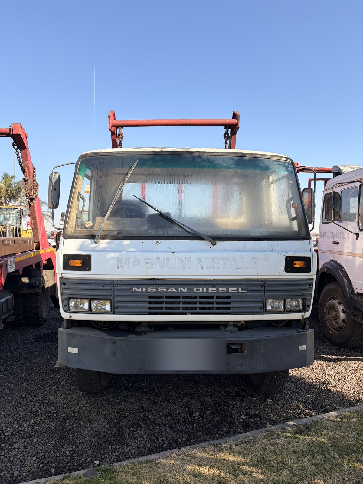 Used Nissan Diesel skip loader truck, head-on view of the grille and cab