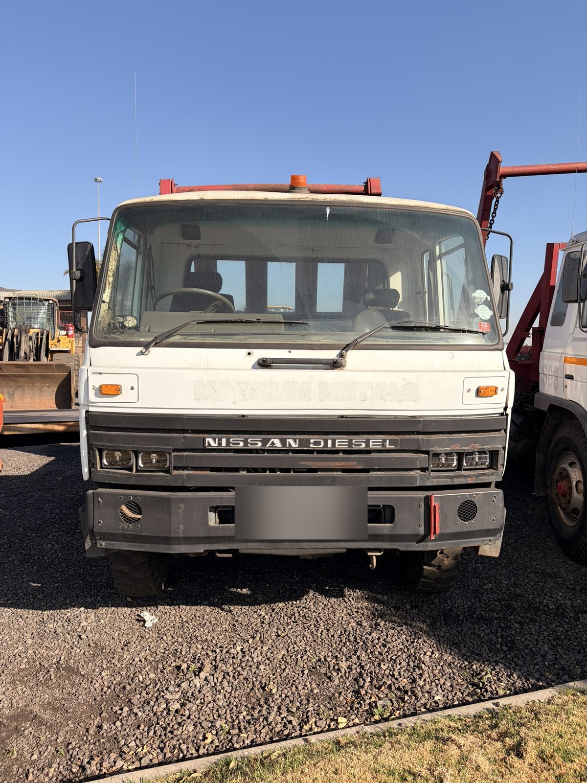 Second used Nissan Diesel skip loader truck, head-on view of the grille and cab