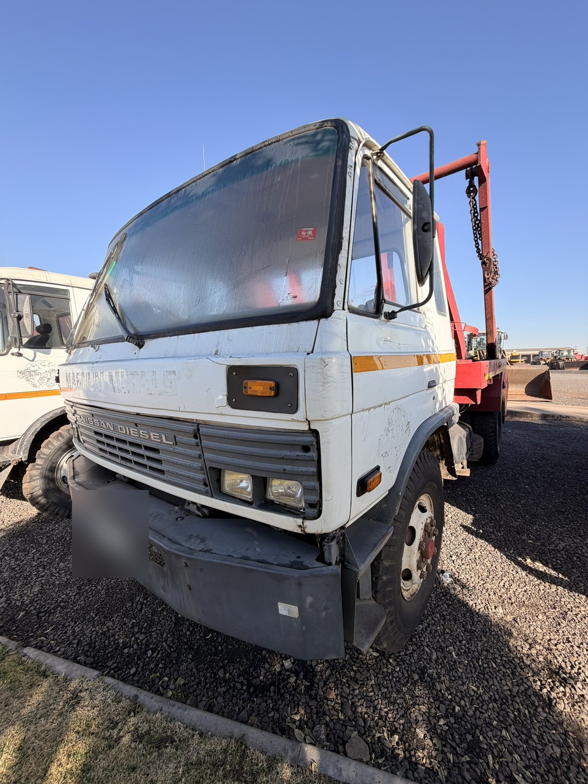 Used Nissan Diesel skip loader truck, front three-quarter view of the cab from the driver's side