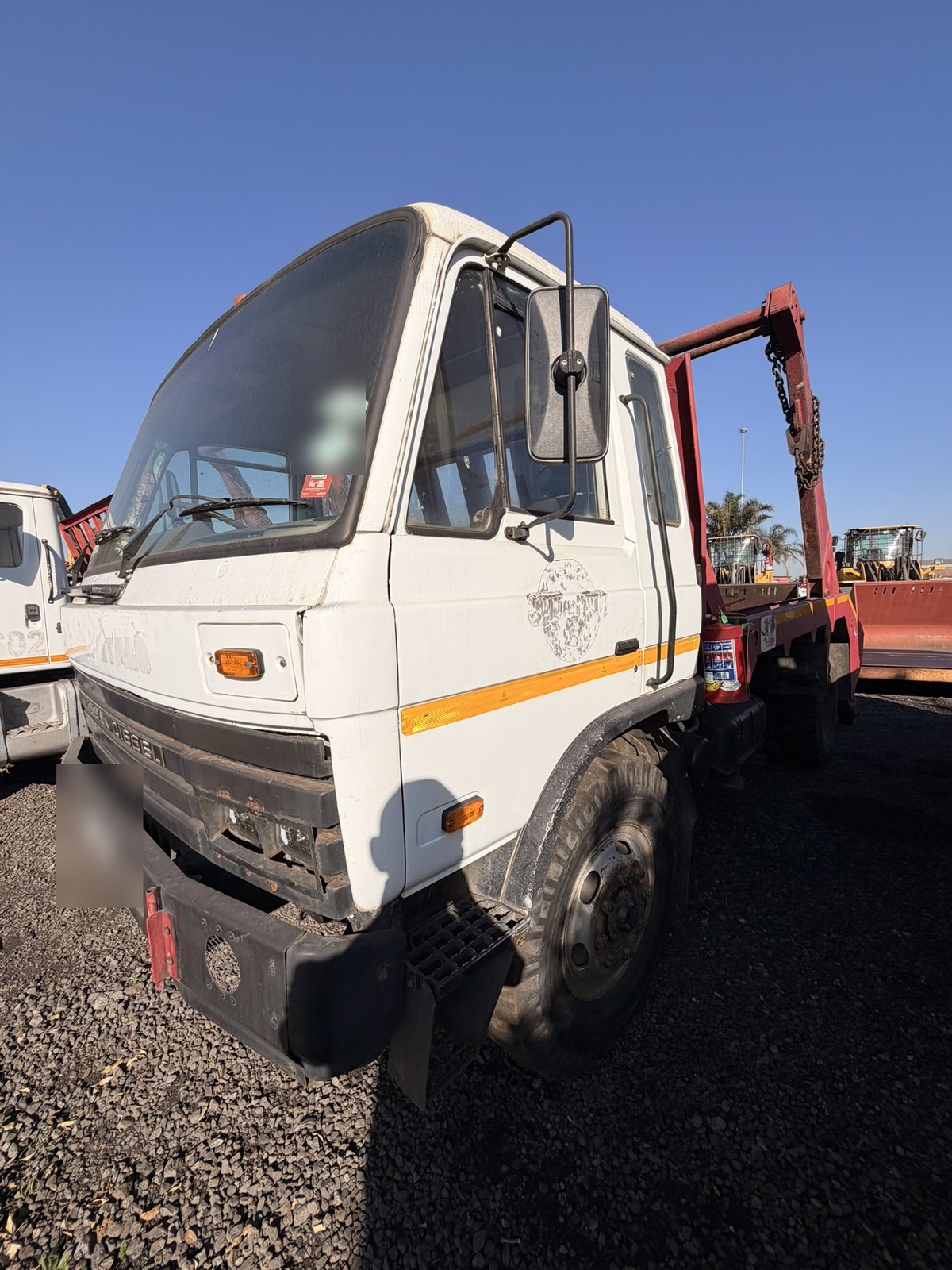 Used Nissan Diesel skip loader truck, front three-quarter view of the cab with the skip gear behind