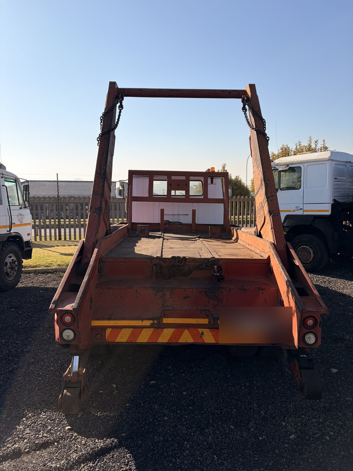 Used Nissan Diesel skip loader truck, rear-on view of the deck and skip frame