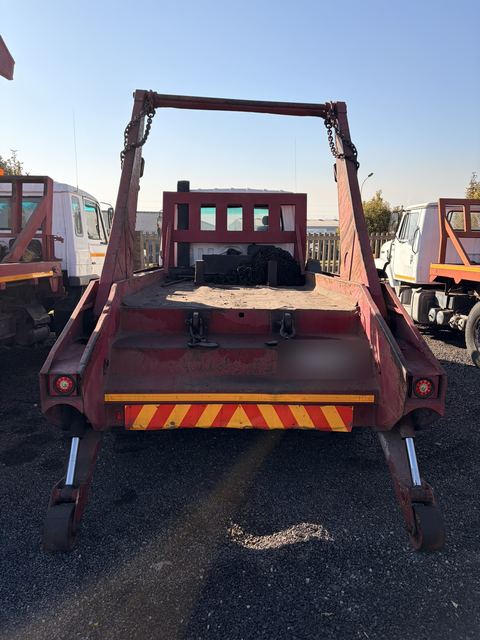 Used Nissan Diesel skip loader truck, rear-on view with the stabiliser legs down