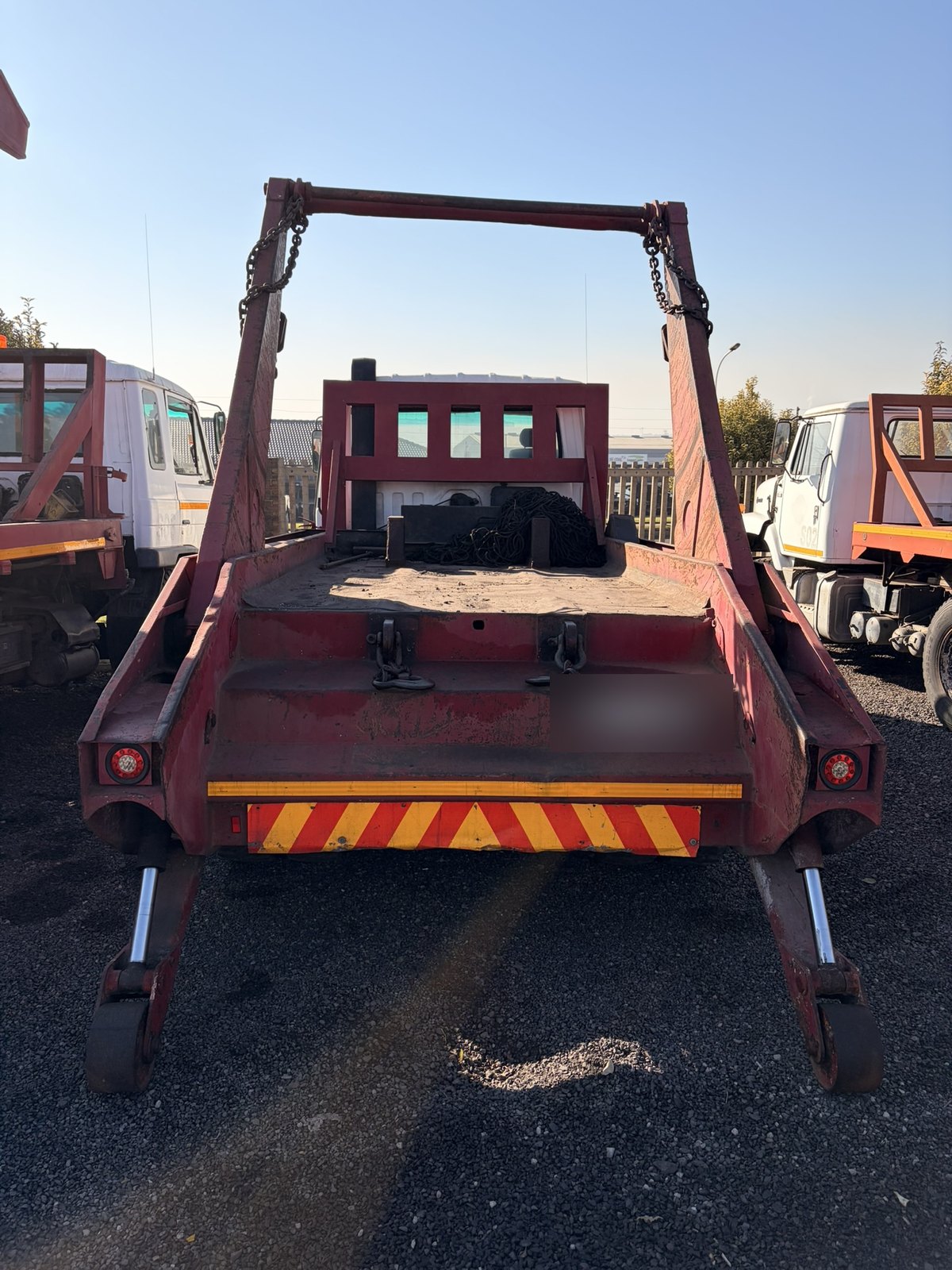 Used Nissan Diesel skip loader truck, rear-on view with the stabiliser legs down
