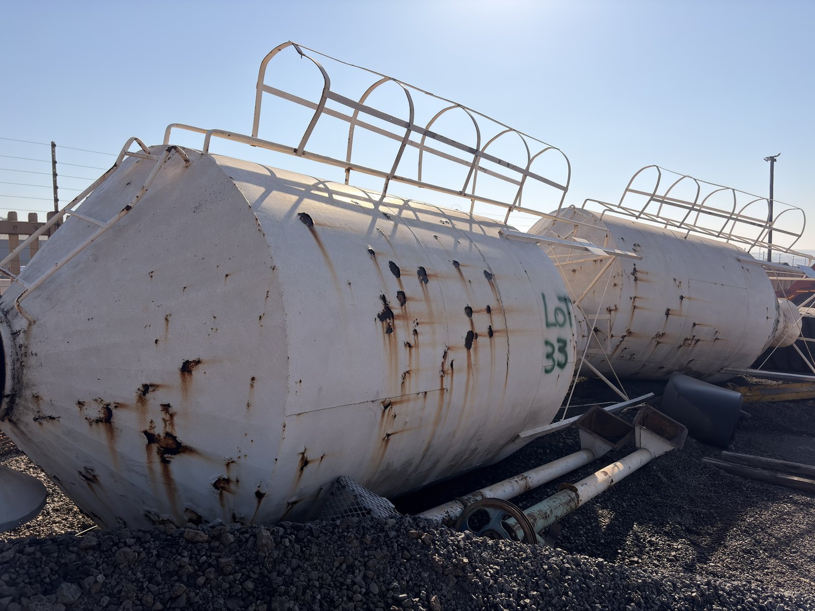 Two used silo bodies lying on the yard, ladder cages uppermost