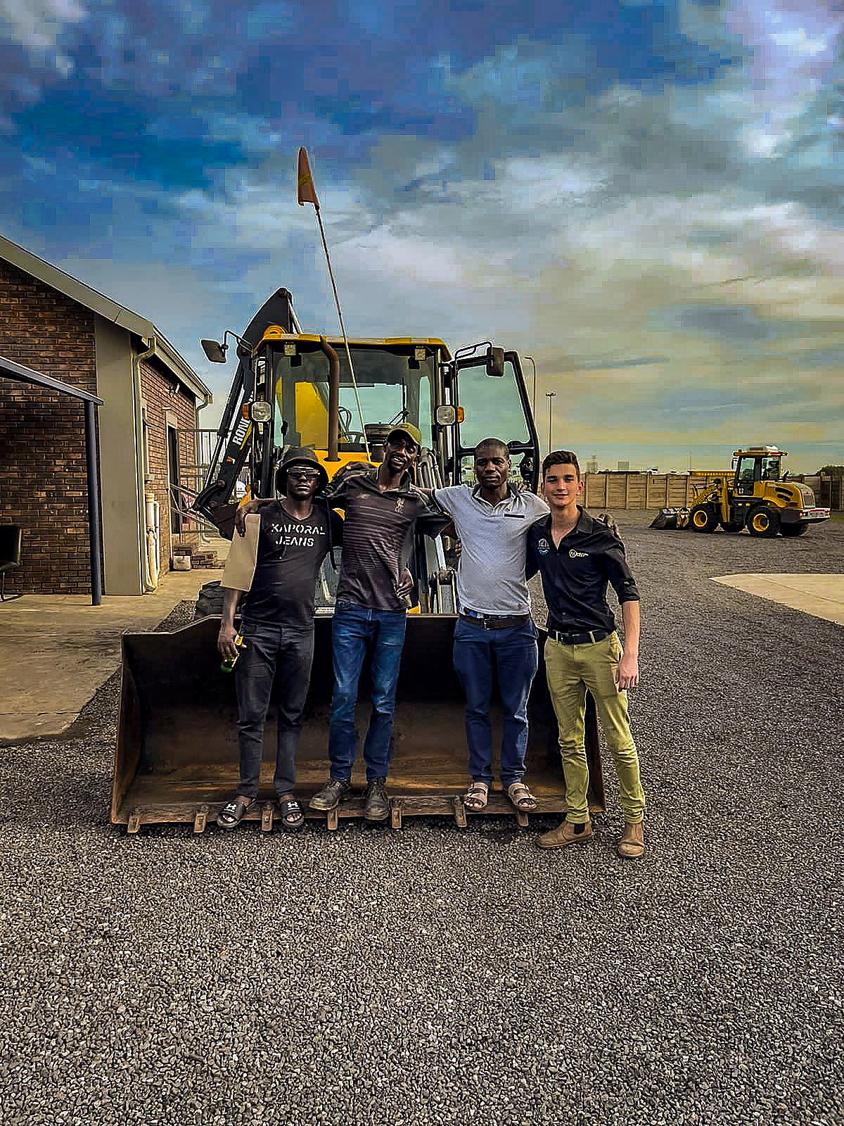 Morne and customers standing in front of a TLB at a handover